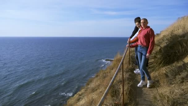 Vacaciones familiares, concepto de estilo de vida. Feliz madre calva, niños en una colina con pintorescas vistas de los altos acantilados y el mar . — Vídeo de stock