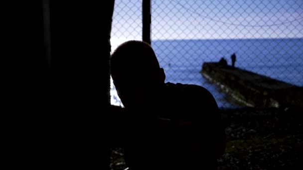 Primo piano. Super rallentatore. silhouette. Boxer batte sacco da boxe in palestra aperta sulla spiaggia con vista mare . — Video Stock