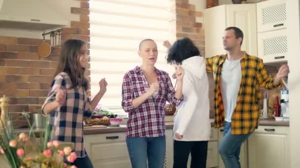 Man, vrouw, jongen en meisje tweeling tieners dansen en lachen samen in de keuken — Stockvideo