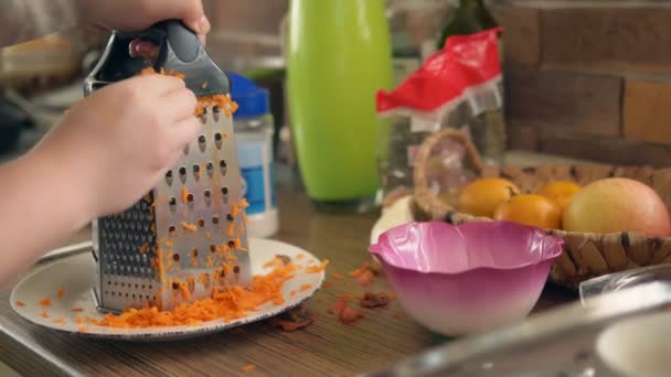 Крупним планом. жіночі руки натирають моркву на тертці — стокове відео