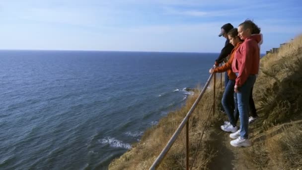 Familjesemester, livsstil koncept. Glad skallig mor, barn på en kulle med pittoresk utsikt över höga klippor och havet. — Stockvideo