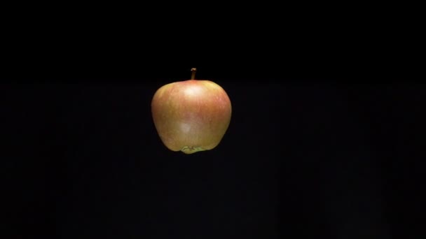 Levitating apple is cut with a knife into two parts of the hand. on a black background — ストック動画