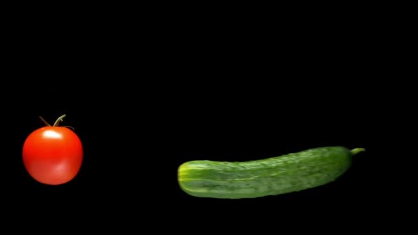 Fresh ripe red tomatoes and green cucumber levitate in the air on a black background. illusionist concept, levitation — ストック動画