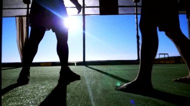 Yakın plan. Süper yavaş çekim. Siluetler. İki erkek boksör deniz kenarındaki bir plajda spor salonunda antrenman yapıyor..