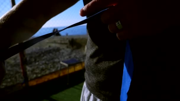 Een close-up. Superlangzame beweging. silhouet. Boxer verbandt zijn hand met een elastisch verband voor het gevecht. in de sportschool op het strand, op de griep van de blauwe zee — Stockvideo