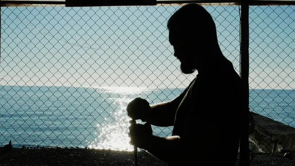 silhouette. Boxer bandages his hand with an elastic bandage before the fight. in the gym on the beach, on the flne of the blue sea