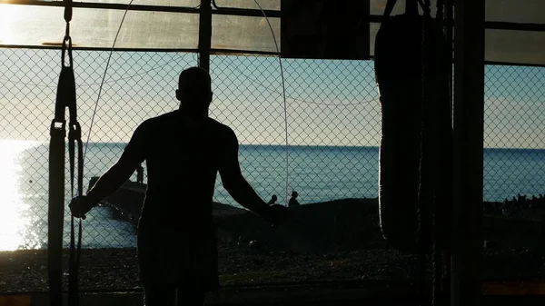 Silhuett. sportig man hoppa rep i utomhus gym på stranden med utsikt över det blå havet och klar himmel — Stockfoto