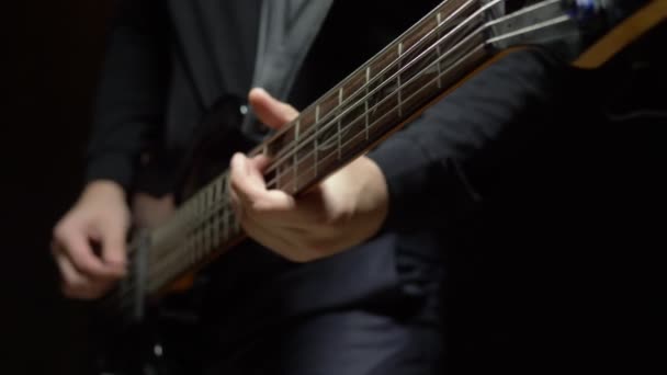 Mann spielt Bassgitarre. dunkler Hintergrund. Langsame Entwicklung — Stockvideo