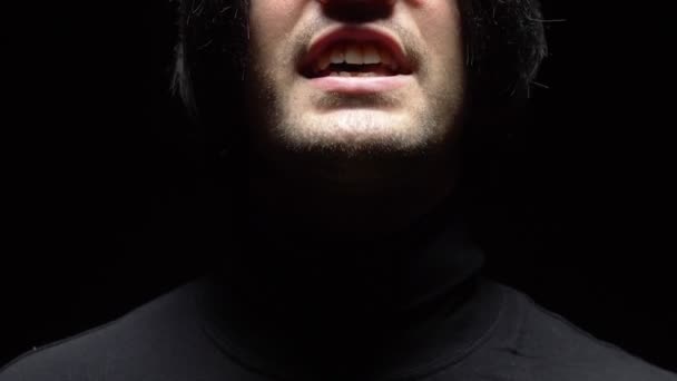Primo piano. volto maschile con cuffie su sfondo nero. bocca che canta — Video Stock