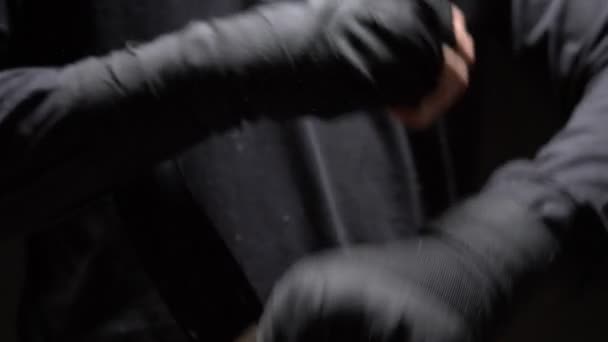 Detailní záběr. mužské ruce ovinuté kolem černého elastického obvazu na ruce. černé pozadí — Stock video