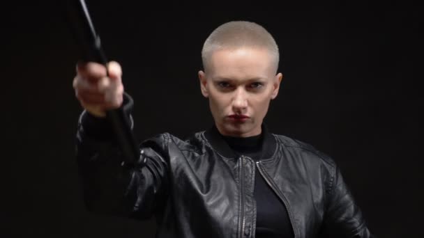 Bella donna bionda dai capelli corti in una giacca di pelle nera con una mazza da baseball su sfondo nero — Video Stock