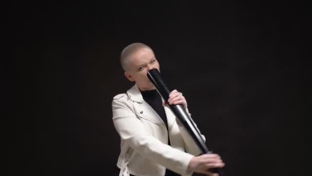 Mooie blonde kortharige vrouw in een witte leren jas met een honkbalknuppel op een zwarte achtergrond — Stockvideo