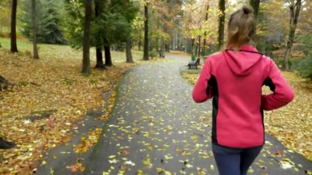 Athletic young girl running in autumn Park after rain. rear view — Stock Video