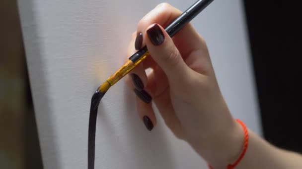 Κοντινό πλάνο. γυναικείο χέρι ζωγραφική με ένα πινέλο μια μαύρη γραμμή σε ένα καθαρό λευκό καμβά — Αρχείο Βίντεο