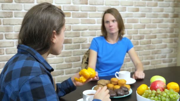 Две девушки лесбиянки пьют чай сидя дома на кухне — стоковое видео