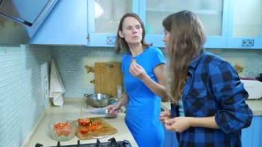 İki kız, lezbiyen aile evdeki mutfakta yemek hazırlıyorlar.