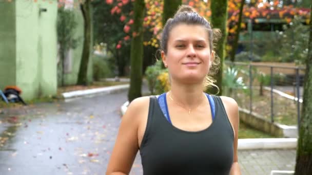 Sporty girl with headphones Jogging in autumn Park — Stock Video