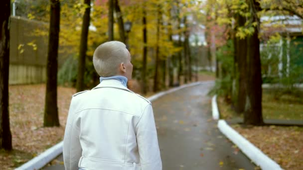 Mujer rubia con estilo con el pelo muy corto caminando en el parque de otoño . — Vídeos de Stock