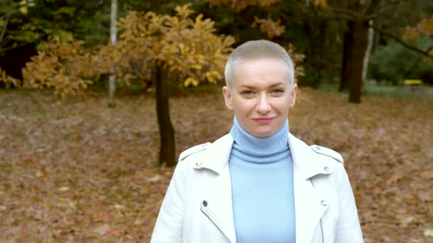 Stylish blond woman with very short hair walking in the autumn Park. — Stock Video