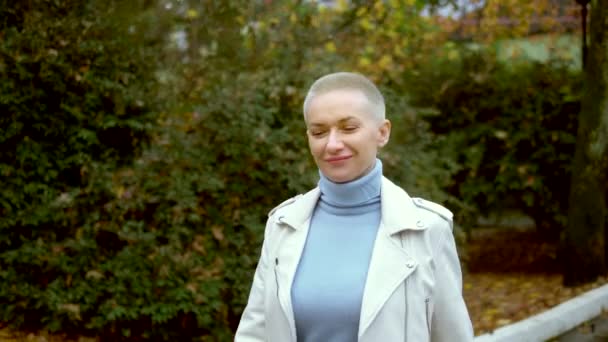 Stylová blond žena s velmi krátkými vlasy procházky v podzimním parku. — Stock video