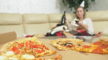 Kız tatilini evde tek başına kutluyor. İçmek, pizza yemek ve telefonu kullanmak.