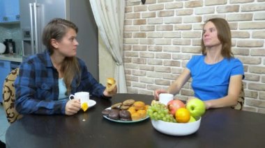 İki kız lezbiyen mutfakta oturmuş çay içiyor.