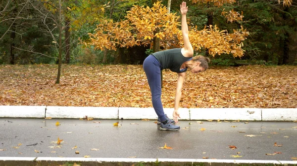 Красива дівчина робить тренування в осінньому парку на тлі змішаного листя — стокове фото