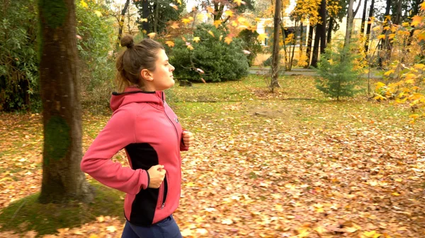 Belle femme avec des cheveux longs jogging dans le parc d'automne. vue latérale — Photo