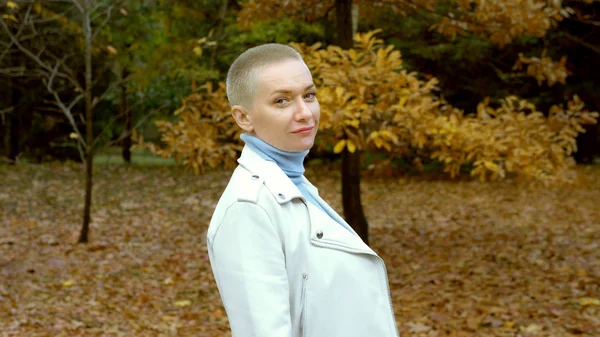 Mujer rubia con estilo con el pelo muy corto caminando en el parque de otoño . —  Fotos de Stock