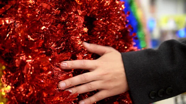 Férfi kéz megérinti színes tinsel a pulton a boltban. Újévi eladás — Stock Fotó