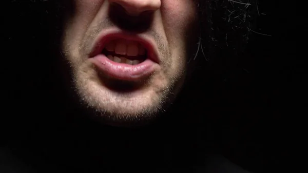 Een close-up. mannelijke mond met kromme tanden schreeuwend. Zwarte achtergrond. — Stockfoto