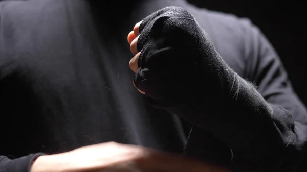 Een close-up. mannelijke handen gewikkeld rond een zwart elastisch verband op de hand. — Stockfoto