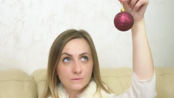 La chica soñando mirando el juguete de Navidad. sostiene bola roja de Navidad — Vídeos de Stock