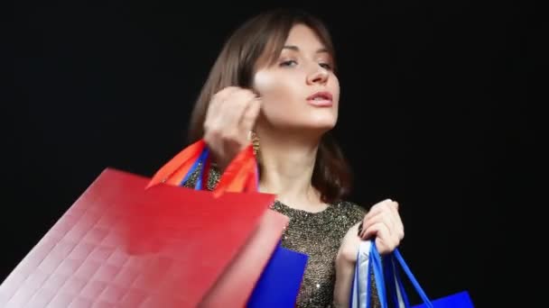 Mooi meisje in gouden jas met pakketten op zwarte achtergrond — Stockvideo