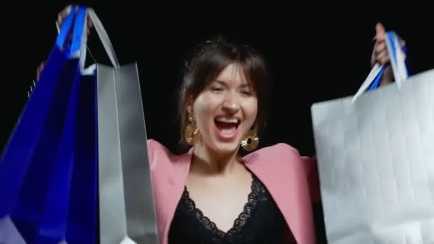 Menina elegante em traje rosa com sacos de papel no fundo preto — Vídeo de Stock