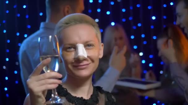 Дівчина після ринопластики з гіпсом на носі танцює на вечірніх друзях . — стокове відео
