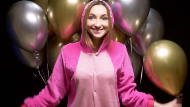 Mädchen in rosa Kigurumi-Pyjamas mit Luftballons. Pyjama-Party — Stockvideo