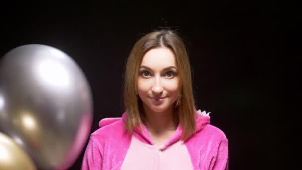 Mädchen in rosa Kigurumi-Pyjamas mit Luftballons. Pyjama-Party — Stockvideo