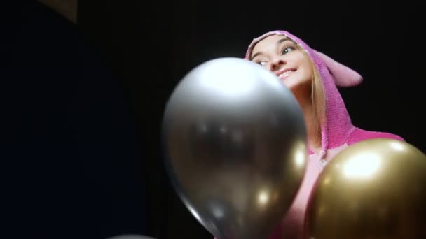 Mädchen in rosa Kigurumi-Pyjamas mit Luftballons. Pyjama-Party — Stockvideo