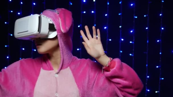 Fată în pijamale roz kigurumi în ochelari VR pe un fundal negru. petrecere pijama — Videoclip de stoc