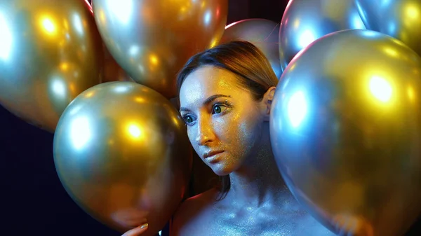 Detailní dívčí tvář se zlatými flitry mezi zlatými balónky — Stock fotografie