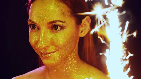 Portrait of a girl with glitter on the face  between the sparklers — Stock Photo, Image