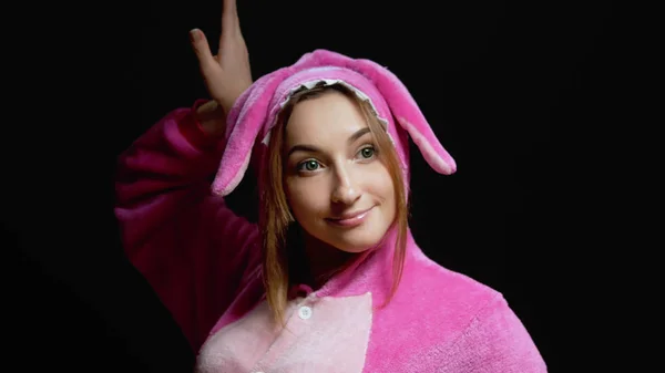 Menina engraçada em macacão kigurumi danças em um fundo preto — Fotografia de Stock