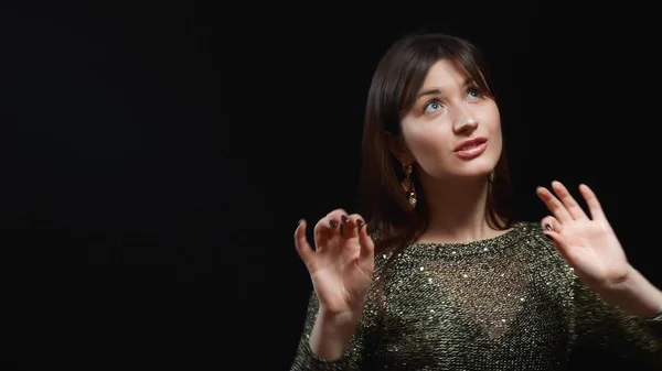 Niña en un vestido de oro y grandes pendientes de oro bailando sobre un fondo negro — Foto de Stock