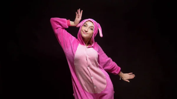 Divertida chica en mono kigurumi baila sobre un fondo negro — Foto de Stock