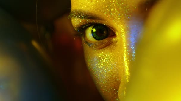 Лицо девушки крупным планом с золотыми блестками среди золотых воздушных шаров — стоковое видео
