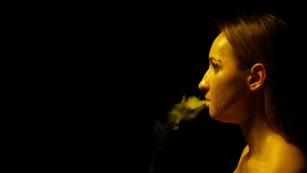 Closeup face of a girl with sparkles in profile. blows smoke out of the mouth — Stock Video