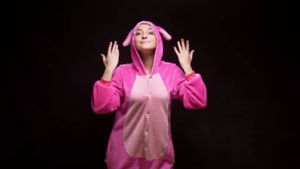 Lustiges Mädchen im Overall kigurumi tanzt auf schwarzem Hintergrund — Stockvideo