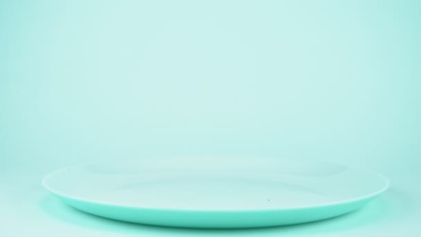Ντοματίνια σε ένα κλαδί που πέφτουν σε ένα μπλε πιάτο. μπλε φόντο — Αρχείο Βίντεο