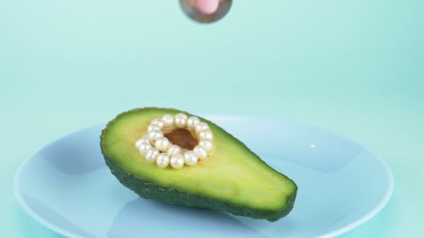 Comida de diseño de moda. medio aguacate con una cadena de perlas, bola de vidrio — Vídeos de Stock